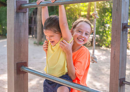 children play in the playgraund. the older girl helps the younger one clim the stairs. protects...