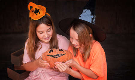 kids girls sitting with pumpkin jack with halloween decorationsの写真素材
