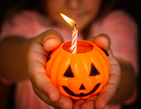 candle in orange candlestick pumpkin halloween on child's handsの写真素材
