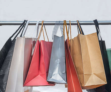 multicolored shopping bags weigh on a hanger on a white backgroundの写真素材