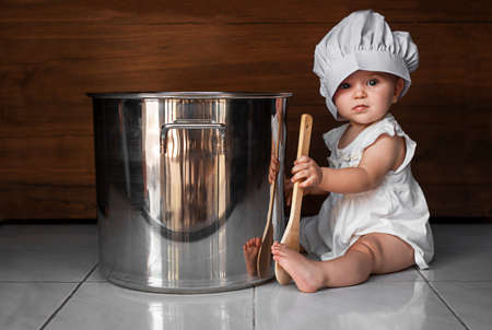 cute baby in the chef hat with a spoon and the large saucepanの写真素材