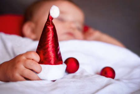 christmas santa hat in the hand of sleeping baby, little christmas ornamentsの写真素材