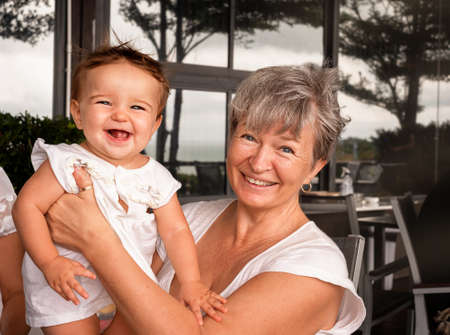 Grandmother in a cafe with a cute granddaughter. woman holding baby in her arms