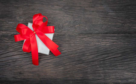 the Gift box with the red bow on wood backgroundの写真素材
