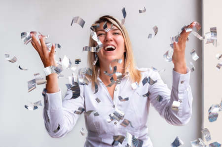 Beautiful happy woman at celebration party with confetti falling everywhere on her. Birthday or New...