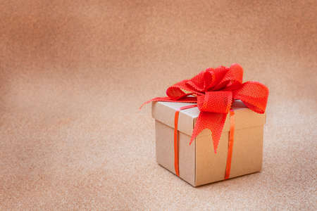 cardboard gift box with red bow on cork background.