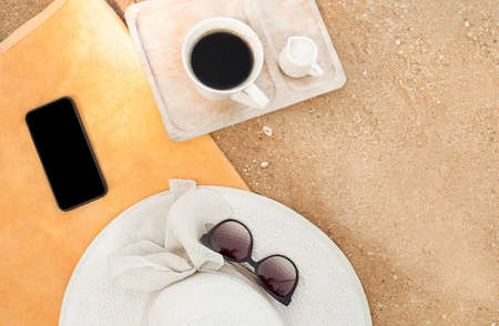 hats on a towel on the beach. childrens and womens hats on an orange towel with a cup on the sandの写真素材