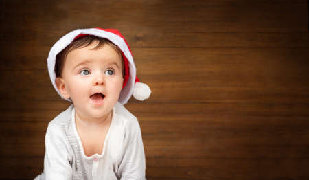 christmas baby portrait on wooden background. child in santa hat smiling