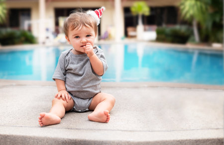 child on vacation on the side of the pool. baby eating a bagelの写真素材