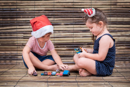 children play toy cars on wooden background. Boy and girl playing together on bamboo background
