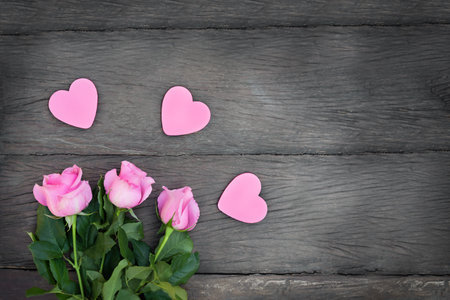 roses with hearts on a wooden background. Pink flowers with pink hearts with copy space on dark wooden backgroundの写真素材