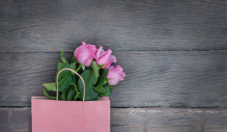 pink paper bag and pink roses on wooden backgroundの写真素材