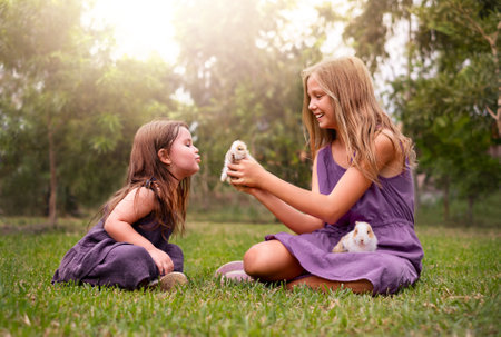 two girls in the park playing with rabbits. children on the grassの写真素材