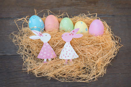 Easter eggs, Easter bunny in the nest on a wooden background. Easter decorations on straw
