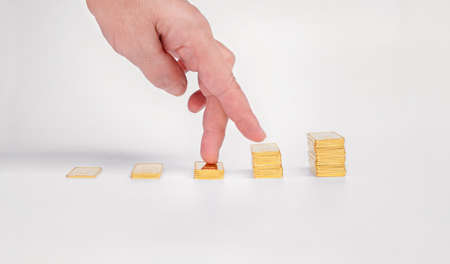 Women's fingers climb the ladder of gold bars. Gold ingot on a light backgroundの写真素材