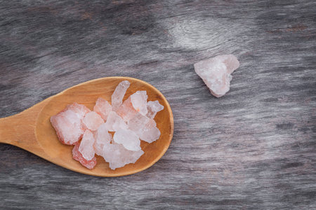 Himalayan pink salt in wooden spoon on wooden backgroundの写真素材