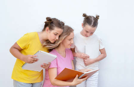 The woman points in a notebook and explains to the children.
