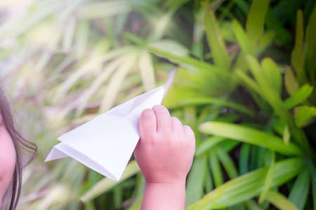 The child holds a paper plane in his hand. Girl playing in the outdoorsの写真素材