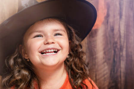 Portrait of the child in the witch hat on the wooden halloween backgroundの写真素材