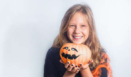 Portrait of a child with Halloween pumpkin in hands on a gray backgroundの写真素材