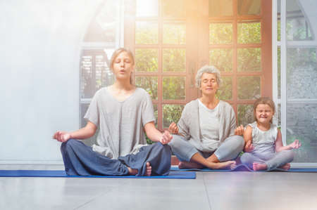Senior with teenager and grandchildren doing yoga at homeの写真素材