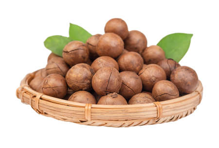 Macadamia nuts with leaves in a straw basket isolated on white backgroundの写真素材
