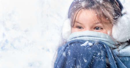 Portrait of the child girl wrapped in the scarf in the winter forestの写真素材