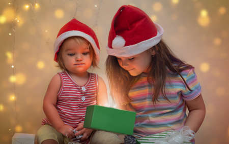 Two children sisters peek into the gift box together