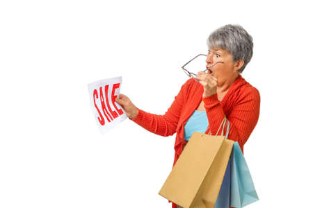Senior woman shopping in surprise looks at the SALE sign on isolated on white background