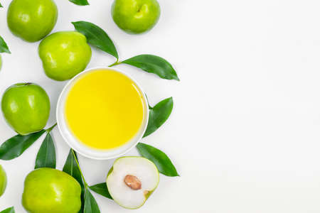 Green fresh jojoba fruit and oil in bowl on white backgroundの写真素材
