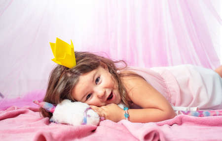 Portrait of a child in a princess costume on the bedの写真素材