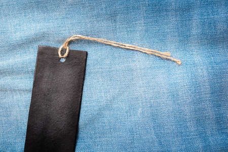 Black cardboard tag on blue jeans background