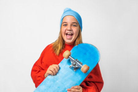 Portrait of a teenage girl in a hat with a skateboard on a gray backgroundの写真素材