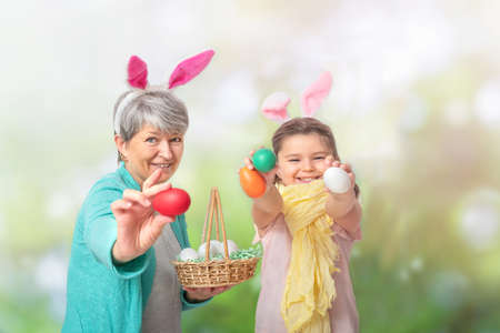 Grandmother and child hold out Easter eggs outdoorsの写真素材