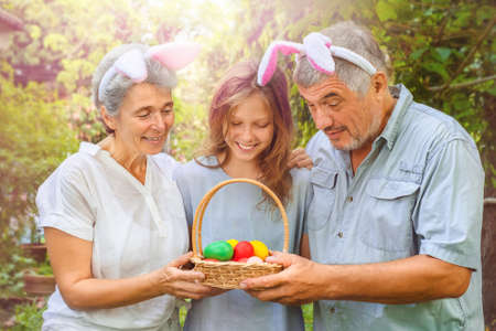 Happy family looking into a basket with Easter eggs in the backyardの写真素材