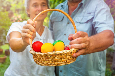 Senior couple holding basket with easter eggs in backyard outdoor