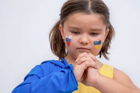 Child with ukraine and russia colors keeps hands together unityの写真素材