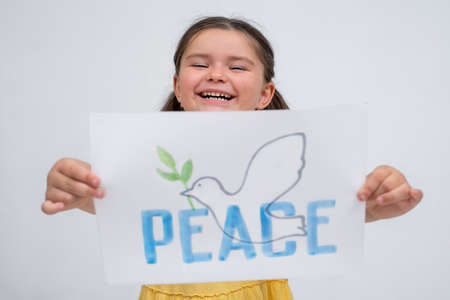 Portrait of a child girl with a poster dove of peace on a gray backgroundの写真素材