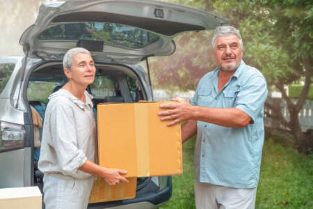 Senior couple carry box from car to new home. movingの写真素材