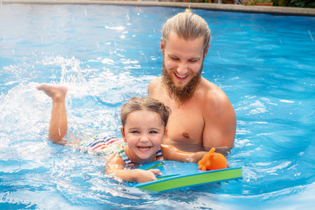 child learns to swim in the pool with dad