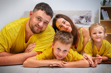 Portrait of a cute family with two children in yellow clothes on the floor together