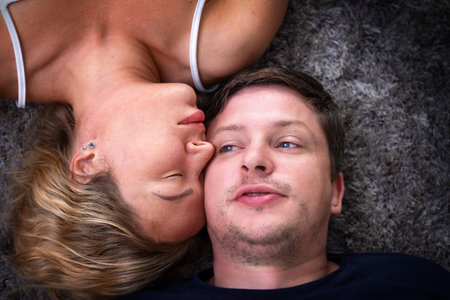 The girl leaned against the guy lying on the floor. View from above