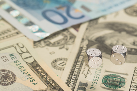 Metal dice lie on the background of paper money.