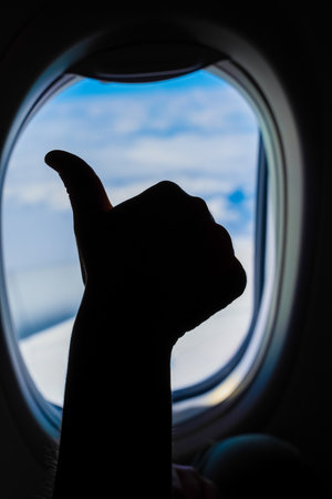Thumbs up from airplane window during flight