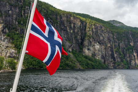 Norwegian flag waving during a boat trip through scenic fjords in Bergenの写真素材