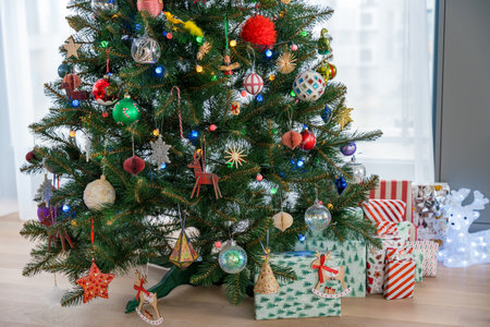 Wallpaper of artificial plastic Christmas tree with gifts, colorful decorations, lights, reindeerの写真素材