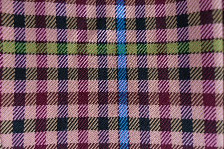 A detailed view of checkered fabric featuring pink, maroon, green, blue, and beige tones.