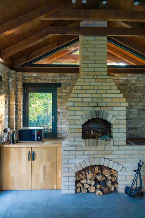 Rustic indoor fireplace with a brick chimney and wood storage, creating a inviting atmosphere.の写真素材
