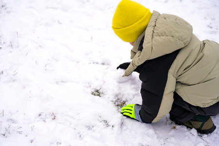 Child in a yellow beanie playing in the snow during winterの写真素材