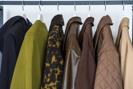 A row of autumn, winter and spring coats in earthy tones hanging on a sleek clothing rack.の写真素材